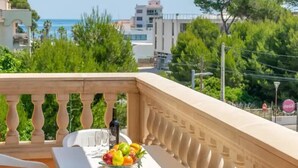 A balcony with a table, a bottle, and a bowl of fruit. - Apartment Son Baulo Llimona (Ca´n Picafort)