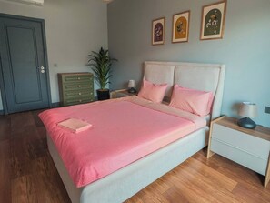 A bedroom with a bed, bedside tables, a dresser, a potted plant, and framed artwork on the wall. - Modern & Central Apartment in Taksim w Pool, Gym, Balcony (Istanbul)