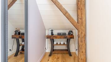 A room with a wooden floor, a mirror, a wooden bench, and a small table with a kettle and cups.