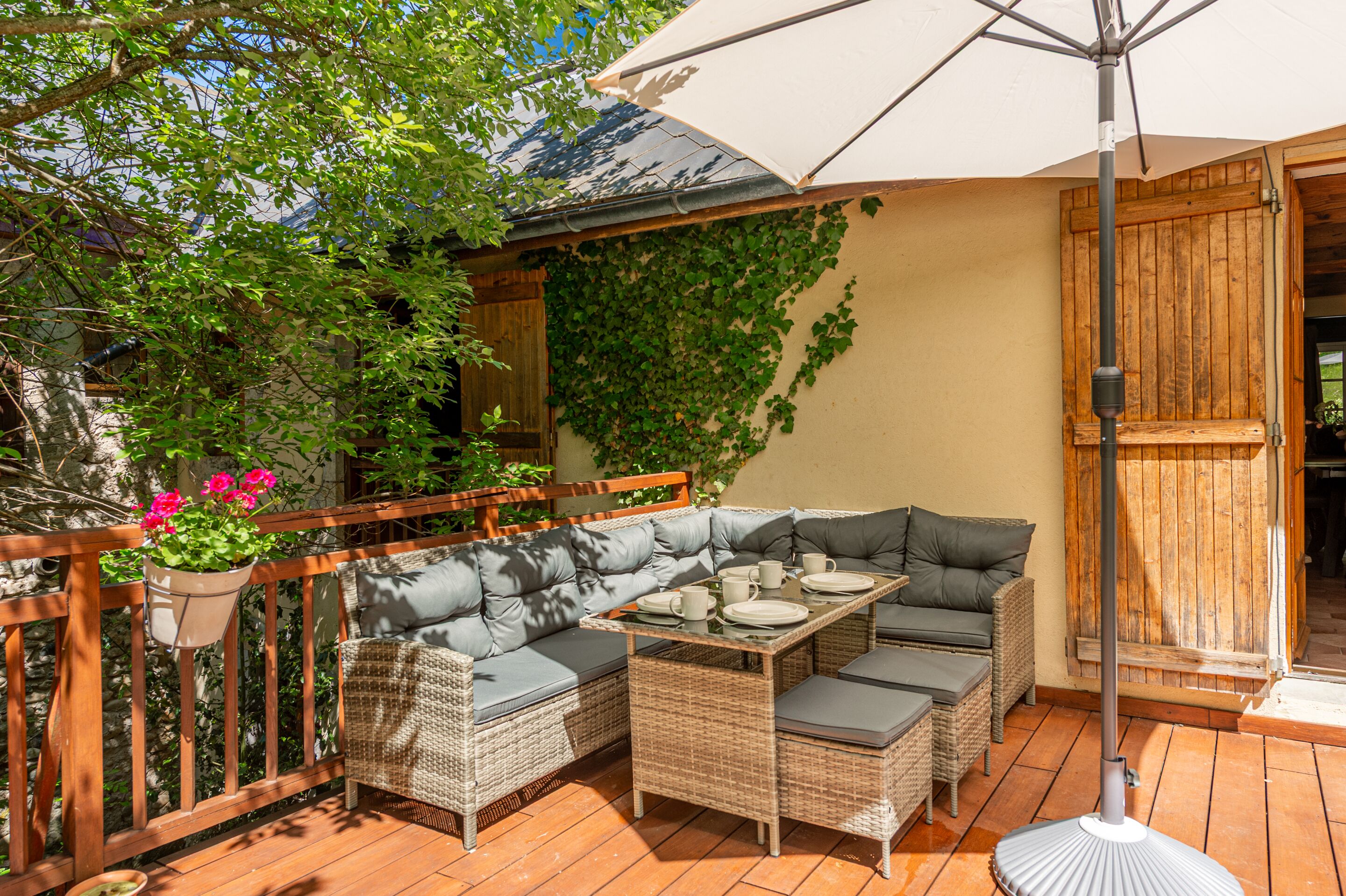 A patio with wicker furniture, a table, and an umbrella.