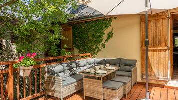 A patio with wicker furniture, a table, and an umbrella.