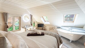 A bedroom with a large bed, a bathtub, a TV, and a window. - Le Moulin de mes garçons (Alby-sur-Chéran)