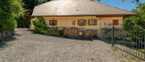 A house with a gravel driveway, wooden shutters, and a metal fence.