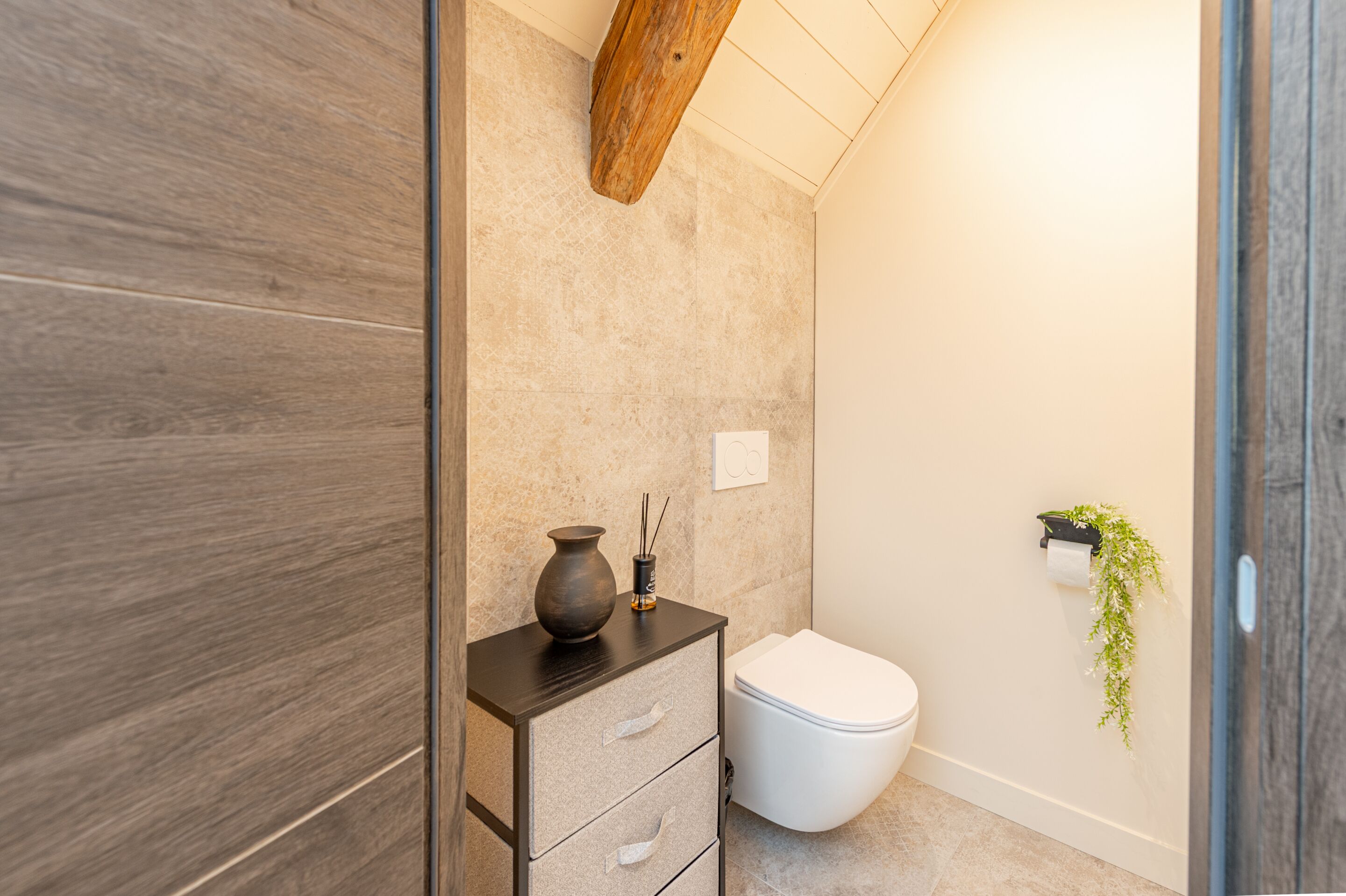 Un baño moderno con tocador de madera, inodoro blanco y dispensador de papel higiénico de pared.
