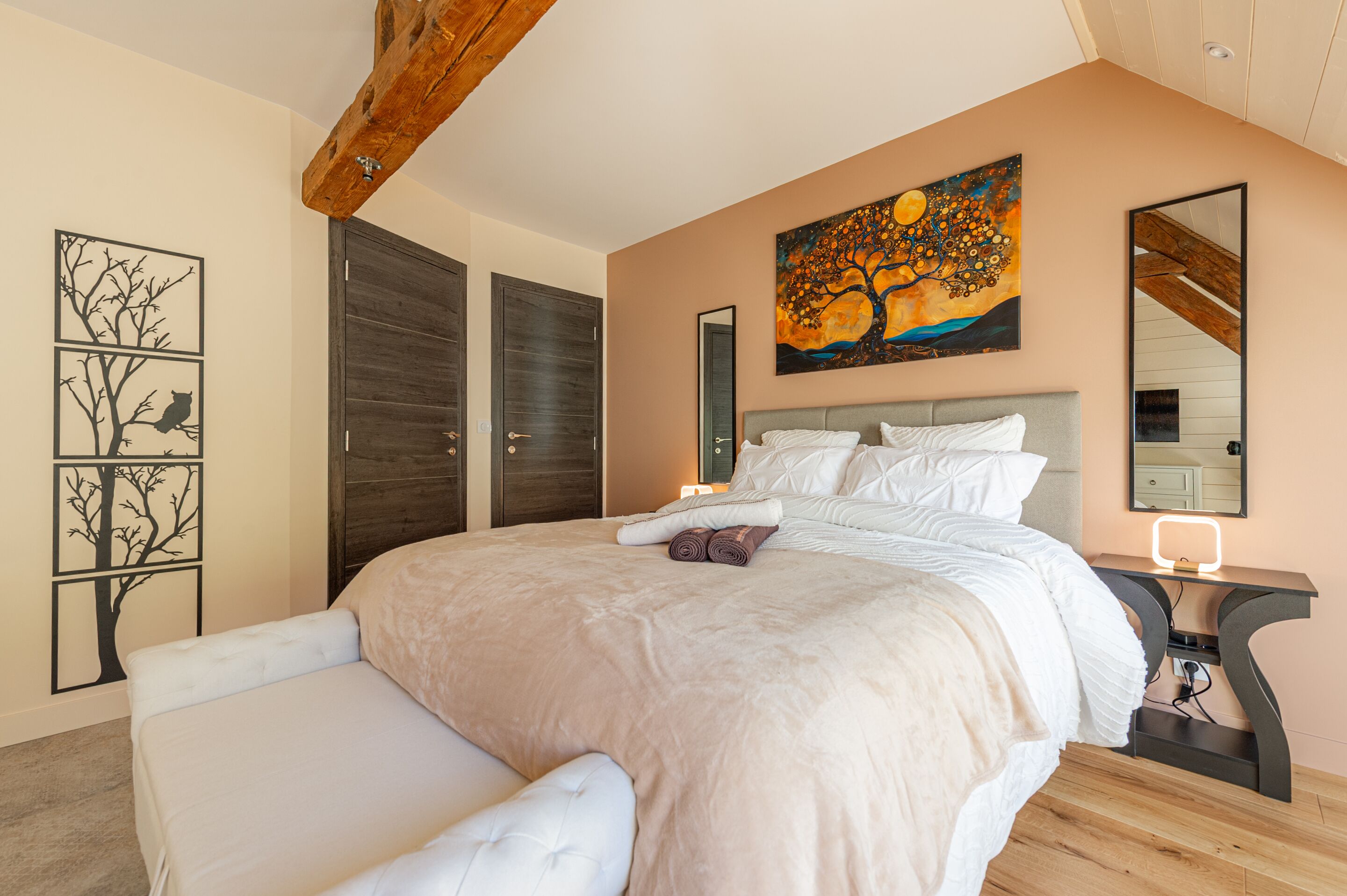 Un dormitorio con una cama grande, una mesita de noche, un espejo en la pared y un cuadro.