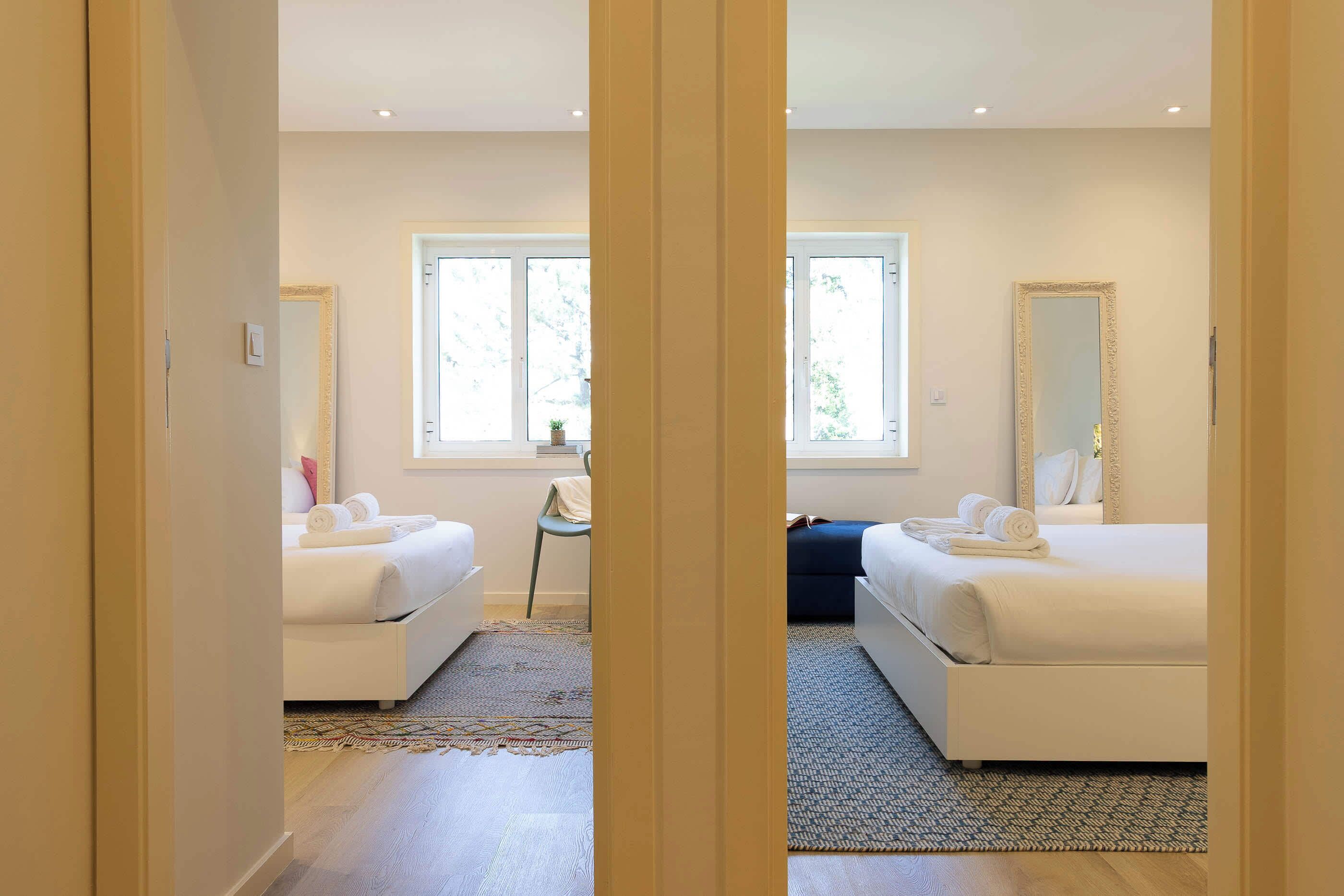 Ein Hotelzimmer mit zwei Betten, einem großen Spiegel und einem Fenster.