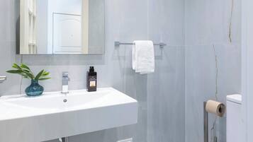 Een moderne badkamer met een witte wastafel, spiegel en toilet.