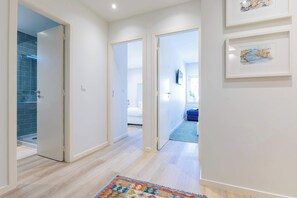 Ein Flur mit Holzboden, einem bunten Teppich und einem Badezimmer mit blauen Fliesen.