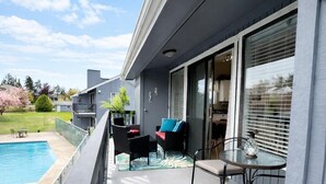 A balcony with a pool, outdoor furniture, and a view of the surrounding area.