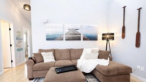 A living room with a brown sectional sofa, a plaid rug, and a wall-mounted lamp.