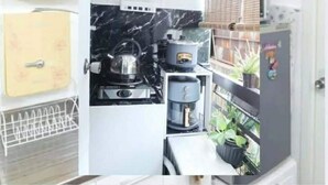 A compact kitchen with a refrigerator, a coffee maker, and a kettle. - One Metropolitan Place (Pasay)