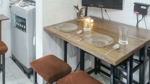 A kitchen with a dining table, stools, a TV, and a refrigerator. - One Metropolitan Place (Pasay)