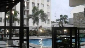 A pool area with a view of a multi-story building in the background. - One Metropolitan Place (Pasay)