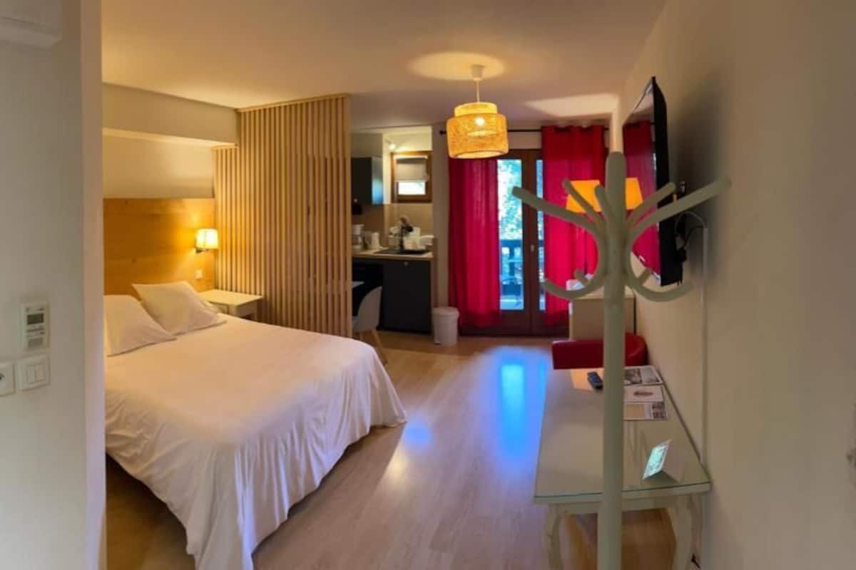 Ett hotellrum med en säng, ett nattduksbord, en lampa och en tv som är monterad på väggen.