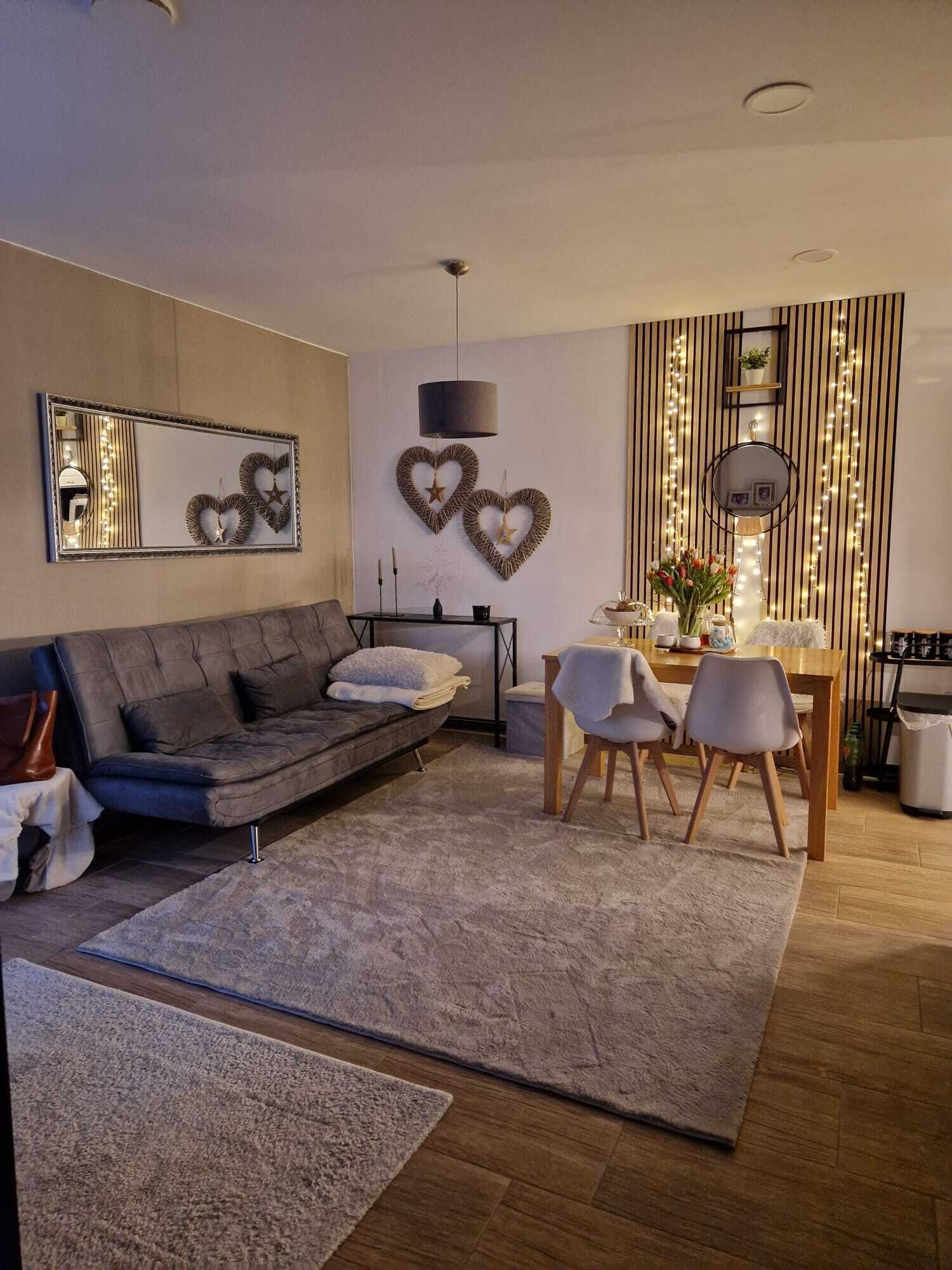 Un salon moderne avec un canapé gris, une table à manger avec des chaises, une table basse et des œuvres d’art décoratives au mur.