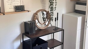 A modern living space with a wooden bench, a black metal console table with books, a white refrigerator, and a decorative mirror. - 🌿 Fantastic vacation apartment, close to the water with terrace & pure nature, near Berlin (Wildau)