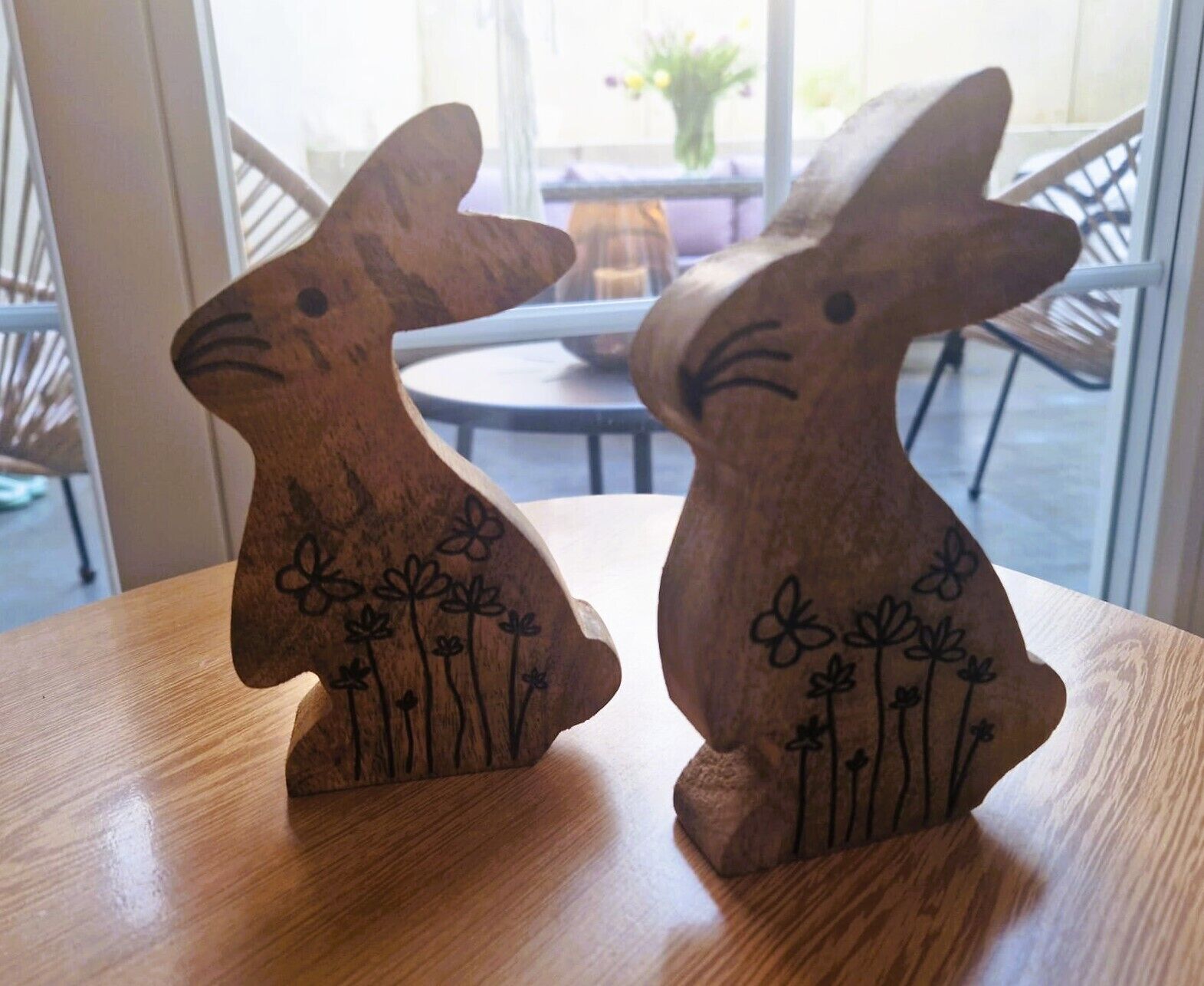 Two wooden rabbit-shaped objects with floral designs on a wooden table.