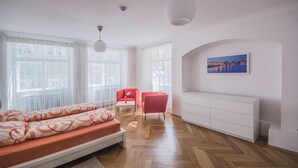 Un salon moderne avec un canapé, un fauteuil rouge, un meuble blanc et un tableau accroché au mur.