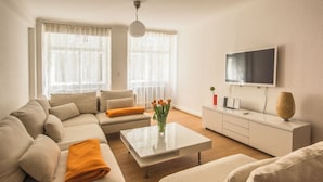 Un salon moderne avec un canapé, une table basse et un téléviseur à écran plat fixé au mur.
