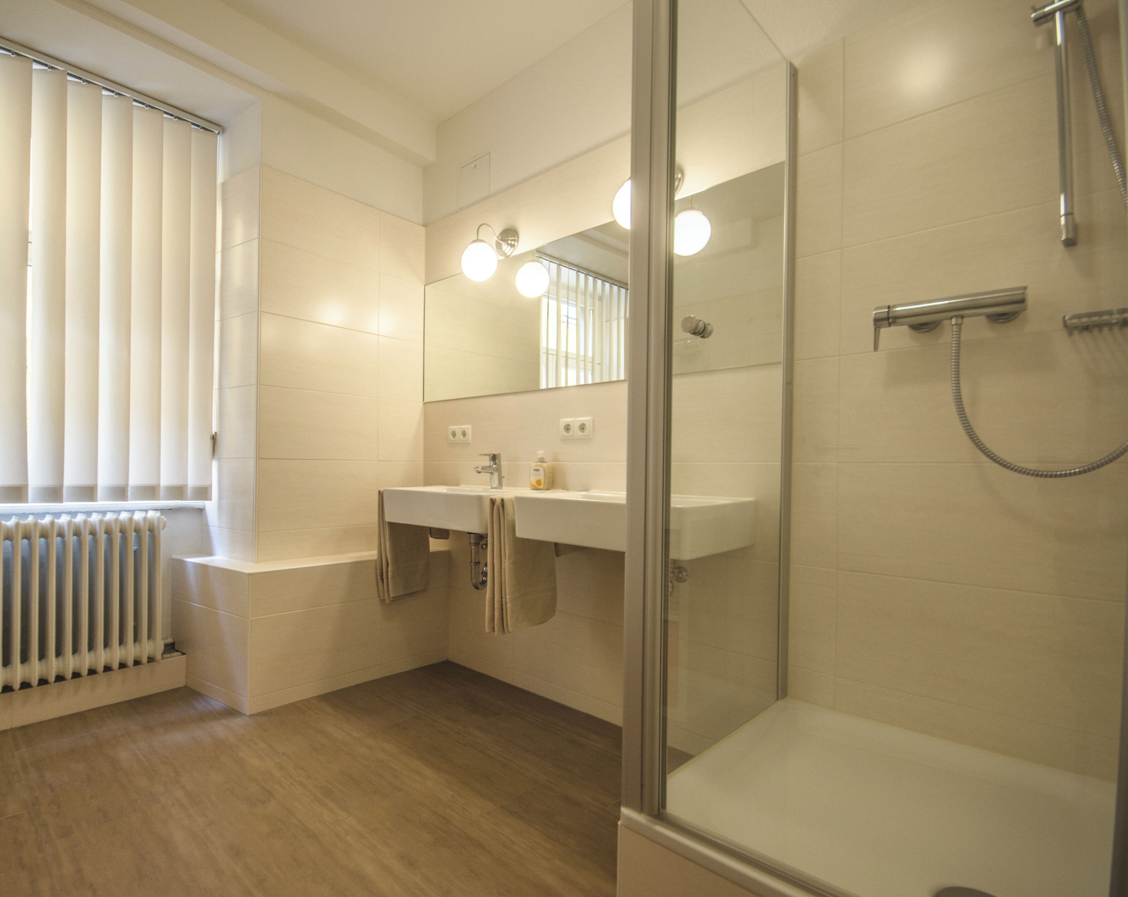 Une salle de bain moderne avec une douche à parois de verre, un meuble-lavabo à deux vasques et un radiateur.