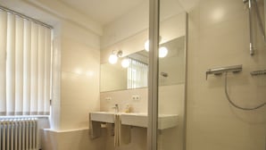 Une salle de bain moderne avec une douche à parois de verre, un meuble-lavabo à deux vasques et un radiateur.