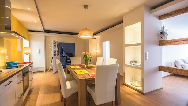 Une cuisine moderne avec des plans de travail en bois, une table à manger avec des chaises et un luminaire suspendu.