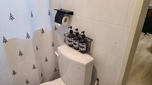 Kylpyhuone, jossa on wc, wc-paperiteline ja saippua-annostelimen teline.