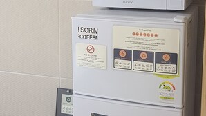 Pieni keittiönurkkaus, jossa on mikroaaltouuni, kahvinkeitin ja roskakori.