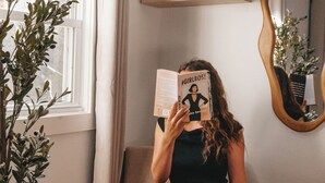 A person sitting on a chair reading a book, with a plant and a mirror on the wall. - Leisure Lake - 3BR Home, Hot Tub, Paddle boats (Scotrun)