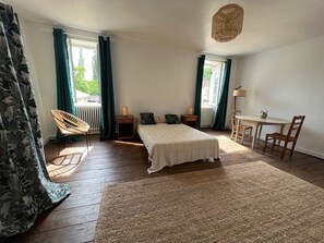 A bedroom with a bed, a chair, a table, and a lamp.