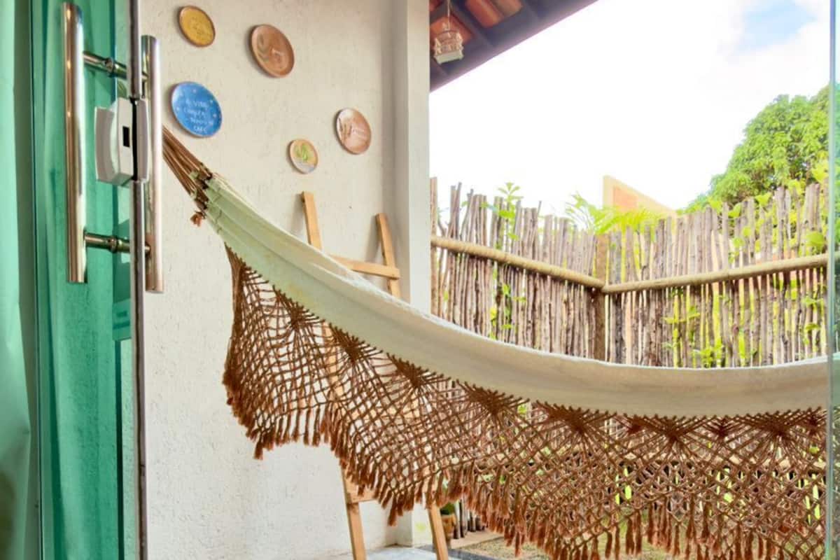 A hammock hanging over a concrete floor, a wooden fence, and a door with a green frame.