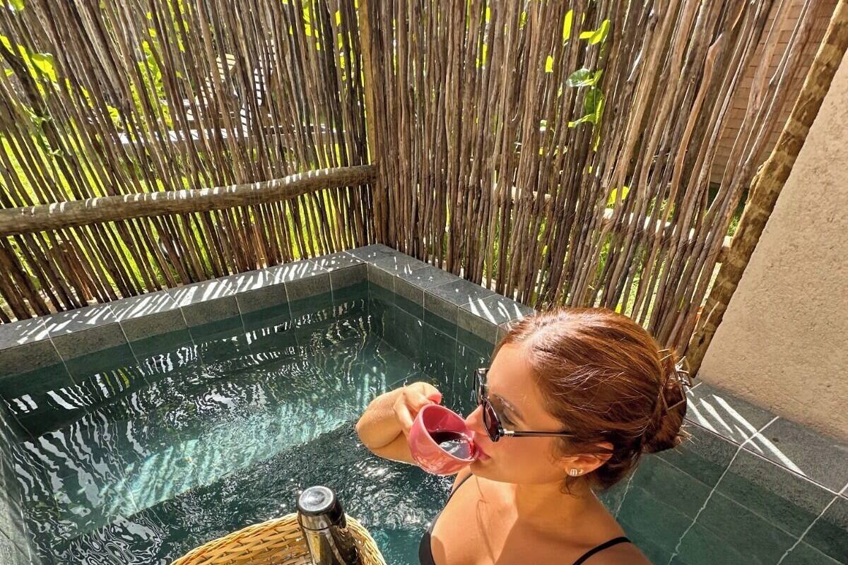 Une personne dans une piscine, avec un plateau de nourriture et de boissons.
