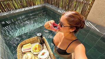 Uma pessoa em uma piscina, com uma bandeja de comida e bebidas.