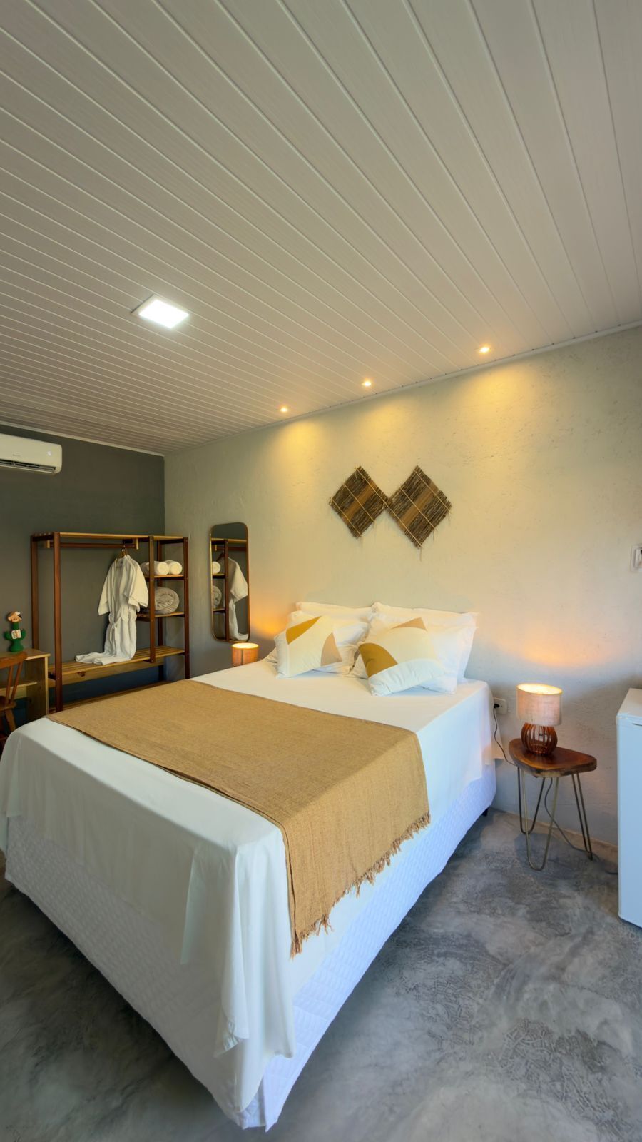 Un dormitorio con cama, mesitas de noche, un espejo y aire acondicionado instalado en la pared.