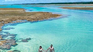 Una zona costera despejada con aguas turquesas poco profundas y formaciones rocosas.