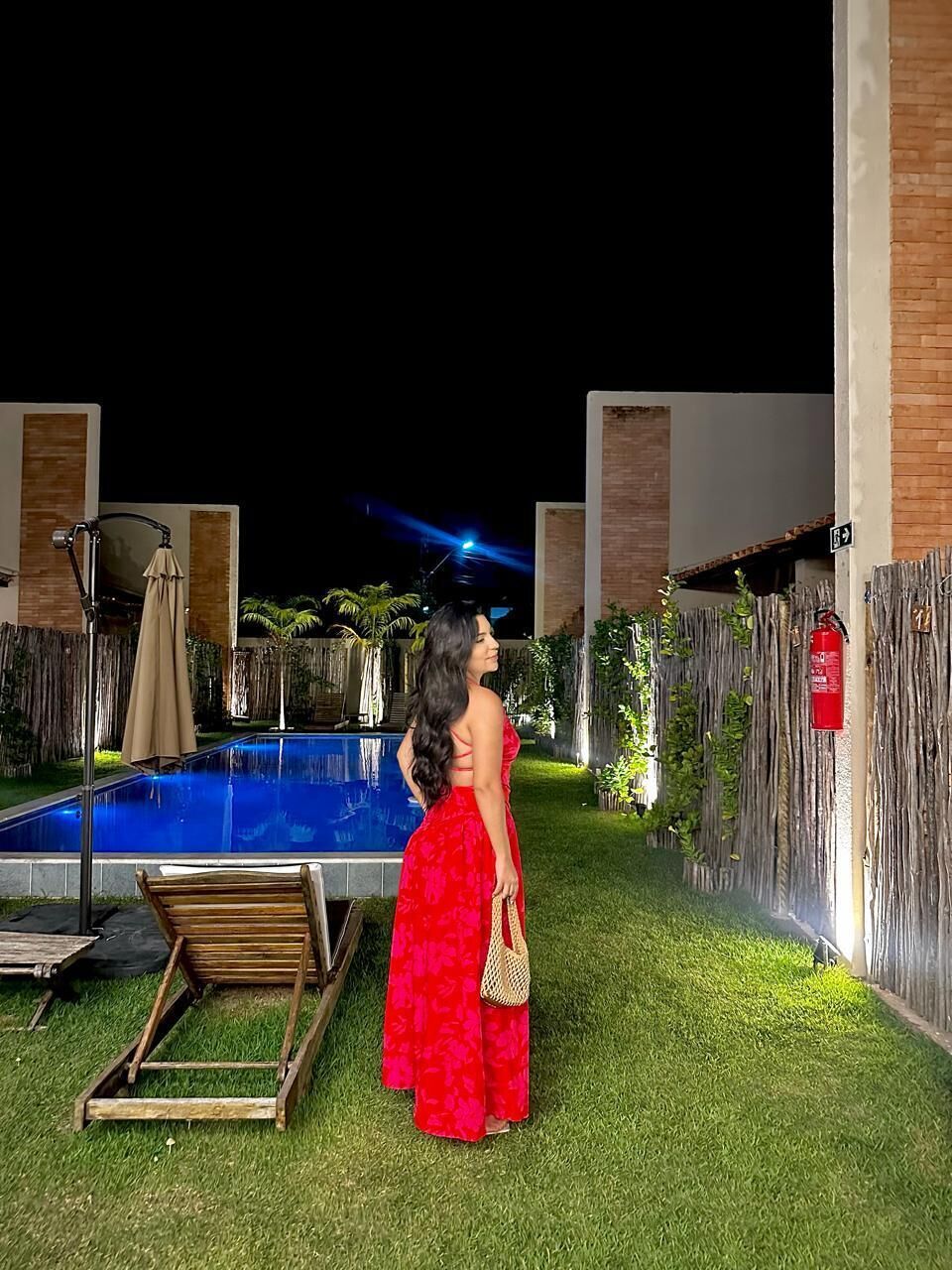 A pool area with a wooden deck, a fire extinguisher, and a fence.