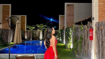 A pool area with a wooden deck, a fire extinguisher, and a fence.