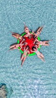 Un grupo de personas dispuestas en círculo alrededor de un flotador inflable en una piscina de color azul claro.
