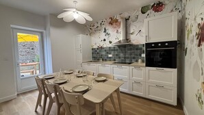 Una cocina moderna con armarios blancos, salpicadero de azulejos y un comedor con mesa para cuatro.