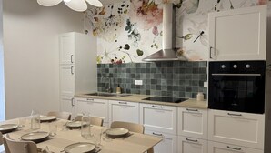 Una cocina moderna con armarios blancos, un horno negro y un salpicadero con motivos florales.