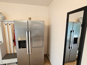 Eine kleine Küche mit einem Edelstahl-Kühlschrank, einer Arbeitsplatte und einem weißen Schrank.