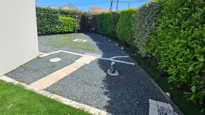 A pathway with a patterned surface, bordered by grass and gravel, leading to a hedge. - Single-storey house with quiet garden - 6 guests (Royan)