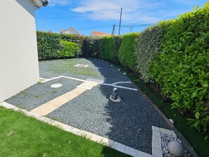 Ein befestigter Weg mit Musterung, gesäumt von Gras und Kies, der zu einer Hecke führt.
