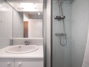 Ein modernes Badezimmer mit einem weißen Waschbecken, einem Spiegel und einer Duschkabine.