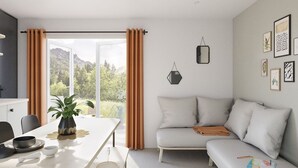Un salon moderne avec un canapé, une table à manger agrémentée d’une plante, et une vue sur l’extérieur.