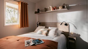 Une chambre à coucher comprenant un lit, une table de chevet, une commode, une fenêtre avec des rideaux et une étagère décorative.