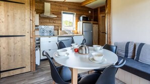 A compact kitchen with a dining area, wooden walls, and a window.