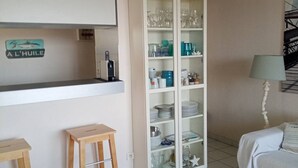 Een keuken met een wit kastje, krukken en een bed met een witte spreidek.