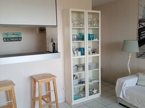 Eine Küche mit weißen Schränken, Barhocker und einem Bett mit weißer Bettdecke.