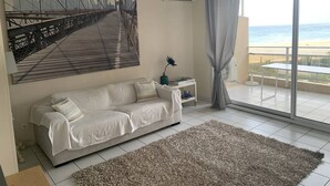 Een moderne woonkamer met een groot raam, een bank, een vloerkleed en een schilderij van een brug.
